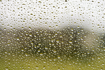 Rain drops on glass window. Dark grey and green textured background. Full frame macro photo. 
