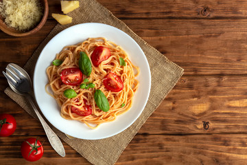Pasta with cherry tomatoes and cheese on a brown wooden background