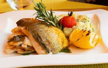 White fish fillet with puree served with lemon and rosemary in a white plate, restaurant setting