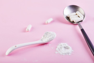 Collagen powder and pills on a pink background. Extra protein intake. Natural cosmetic supplement for skin, bones, joints and intestines. A plant or fish based.