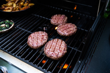 burgers on the bbq grill with potato wedges in pan and giant mushrooms