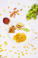 Breakfast includes Almonds, Corn Flakes, Apple and Grapes isolated with blur white background filled with ingredients.