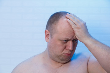 Fototapeta premium Portrait of a bald man who holds his head.