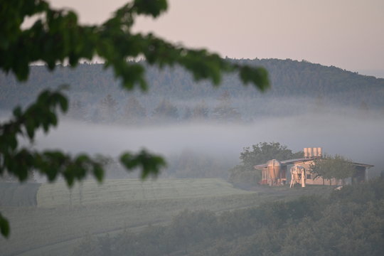 Geb&auml;ude zwischen Wiesen und Morgennebel bei Berglen