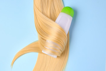 Fototapeta na wymiar Bottle of shampoo for blonde hair on color background
