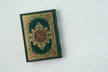 Holy Quran with written arabic calligraphy meaning of Al Quran on white background.