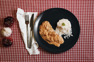blue dish of chicken strogonoff on a red and white horizontal tablecloth