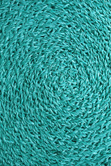 Vertical image of spiral texture of turquoise blue colored woven water hyacinth place mat 