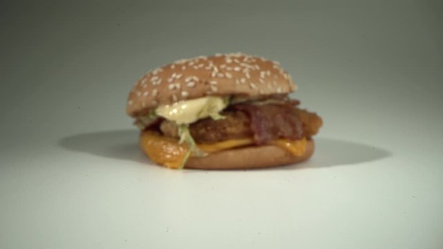 The camera slowly approaches the freshly prepared delicious cheeseburger. White background