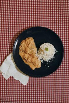 vertical photography of chicken strogonoff with rice in rustic tablecloth