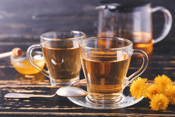 Cups of healthy dandelion tea on dark wooden background