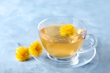 Cup of healthy dandelion tea on color background