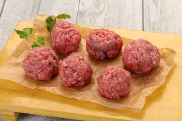 Raw meatball over wooden background