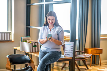 Young woman holding a smartphone and typing a message
