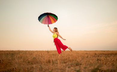 Woman flying on umbrella against sundown sky