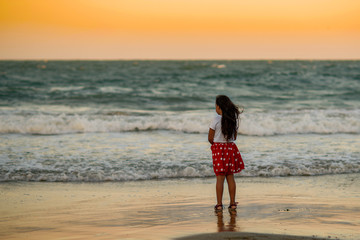  little girl  on sea shore look at warm summer sunset