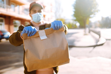 Сourier delivers a bag of food and coffe in quarantine city. Delivery service concept. Covid-2019.