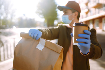Сourier delivers a bag of food and coffe in quarantine city. Delivery service concept. Covid-2019.