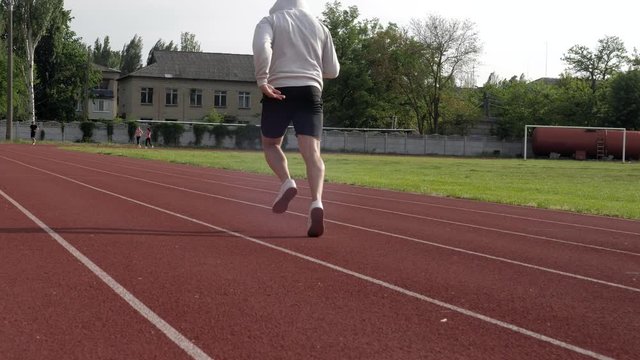 young sprinter accelerates speed while running on race track