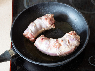 raw skinned Oxtails (tails of cattle) frying in pan on ceramic stove at home kitchen