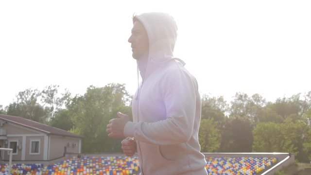 Bodybuilder running and jogging on the fresh air on a stadium in the sunset