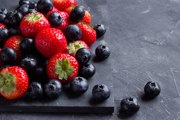 Strawberries and blueberries on a dark background close up