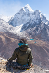 A trekker sitting and enjoying Ama Dablam mountain peak view from Nangkart Shank view point in Everest base camp trekking, Nepal