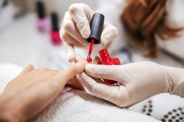Closeup of beautician putting nail polish on woman’s nails.