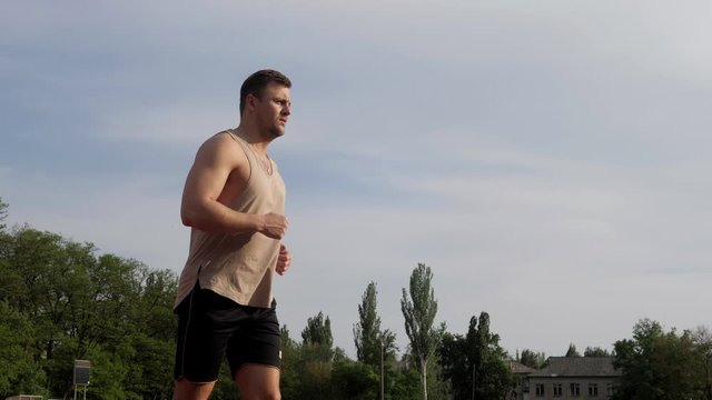 Bodybuilder running and jogging on the fresh air on a race track outdoors