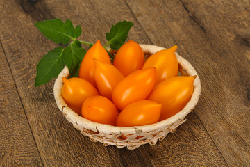 Yellow tomato heap in the wooden bowl