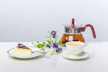 Teatime with slice of basque burnt cheesecake and cup of tea on table.
