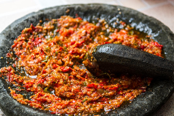 Grinding chili in a traditional stone grinder or sambal ulek