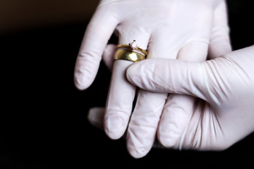 Engagement ring on woman`s hand in protective medical latex gloves. Love relationship in quarantine. Marriage and risk of viral spread. 