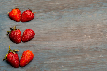 strawberries in form heart, on table blue, conceptual for white.