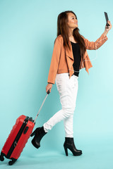 asian woman travel with red hard case bag holding passport and smart phone for flight check in