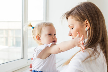 Young mother playing with her baby girl at home. Motherhood, infant and children concept.