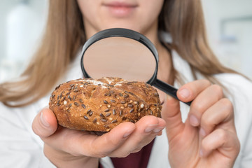 Scientist examines a kaiser bun with magnifying glass