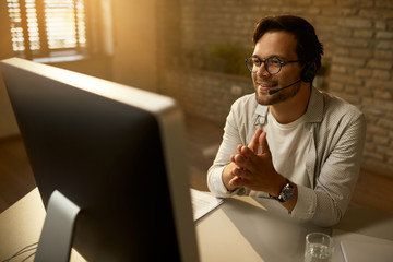 Smiling entrepreneur having online meeting over desktop PC in the office. - obrazy, fototapety, plakaty