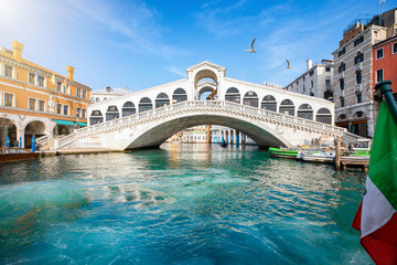 Blick auf die Rialto Brücke in Venedig, Italien, ohne Menschen, mit klarem, smaragdgrünen Wasser im Kanal und Sonnenschein - obrazy, fototapety, plakaty