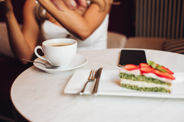 Beautiful caucasian female with long blonde wavy hair sits on the sofa, drinks coffee