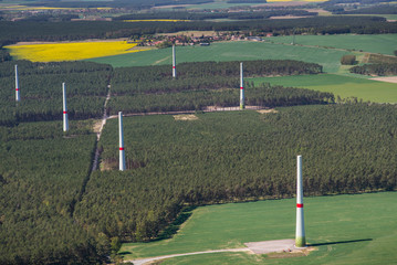 Wind turbine construction site area in a forest and on the field, - only the towers are built -...