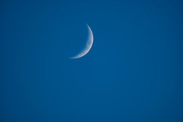 Moon edge over deep clear blue sky