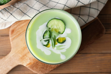 Glass with cold cucumber soup on table