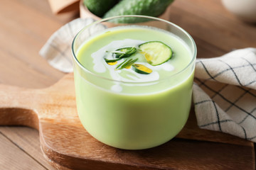 Glass with cold cucumber soup on table