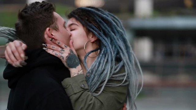 Young happy loving couple walking outdoors at the street having fun. Couple Holding Hands. Couple in love fun and joy hugging spinning together. woman with dreadlocks. kiss