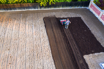 aerial view of Farmer plows the garden with a cultivator, preparing it for planting vegetables, on a sunny day garden