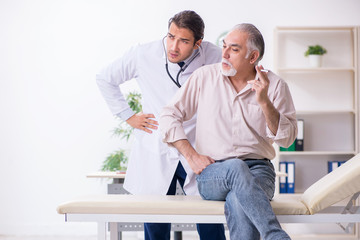 Fototapeta premium Young male doctor and old patient in antismoking concept