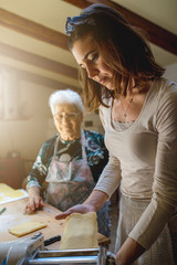 Caucasian grandmother and granddaughter preparing dough for making fresh homemade pasta. Spending...