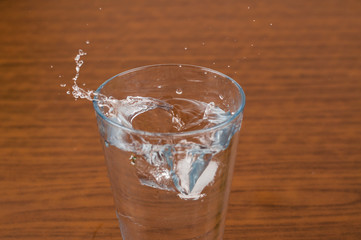 A glass and an ice cube on a wooden table