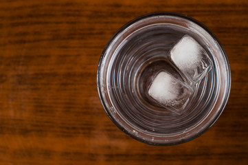 A glass and an ice cube on a wooden table